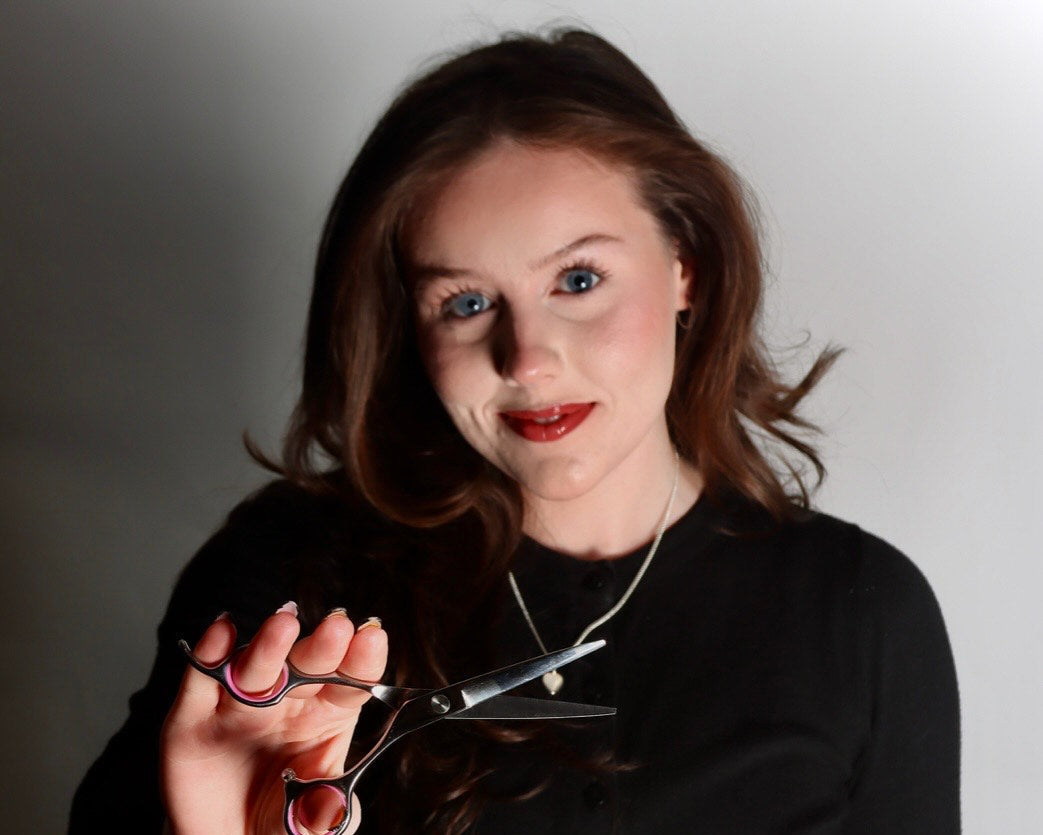 Person holding scissors against a plain background