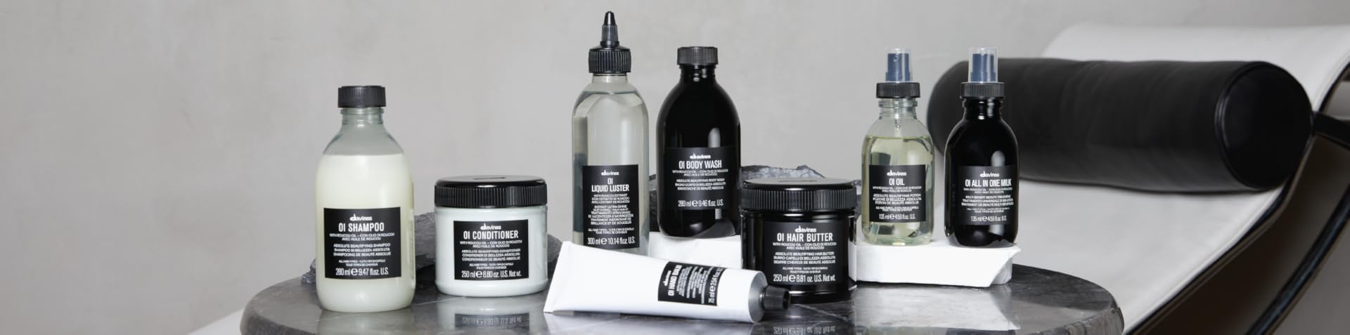 davines oi Collection of skincare and hair care products on a gray surface with a white background bombshell collar city salon and suites troy ny